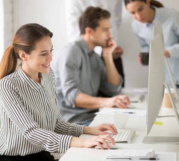 Beautiful smiling young businesswoman working on desktop computer in office
